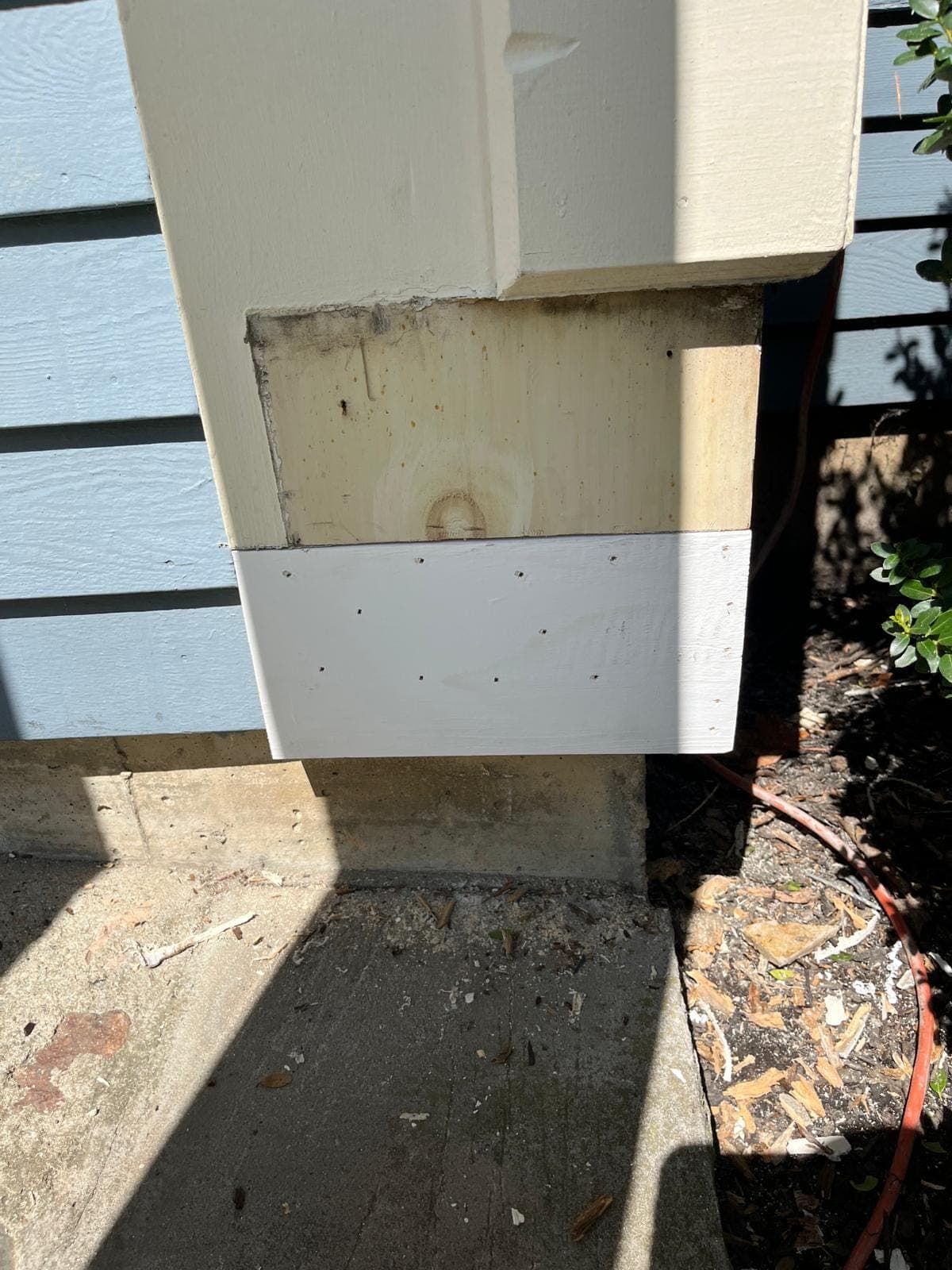 A new primed corner board fitted against grey clapboards, close up