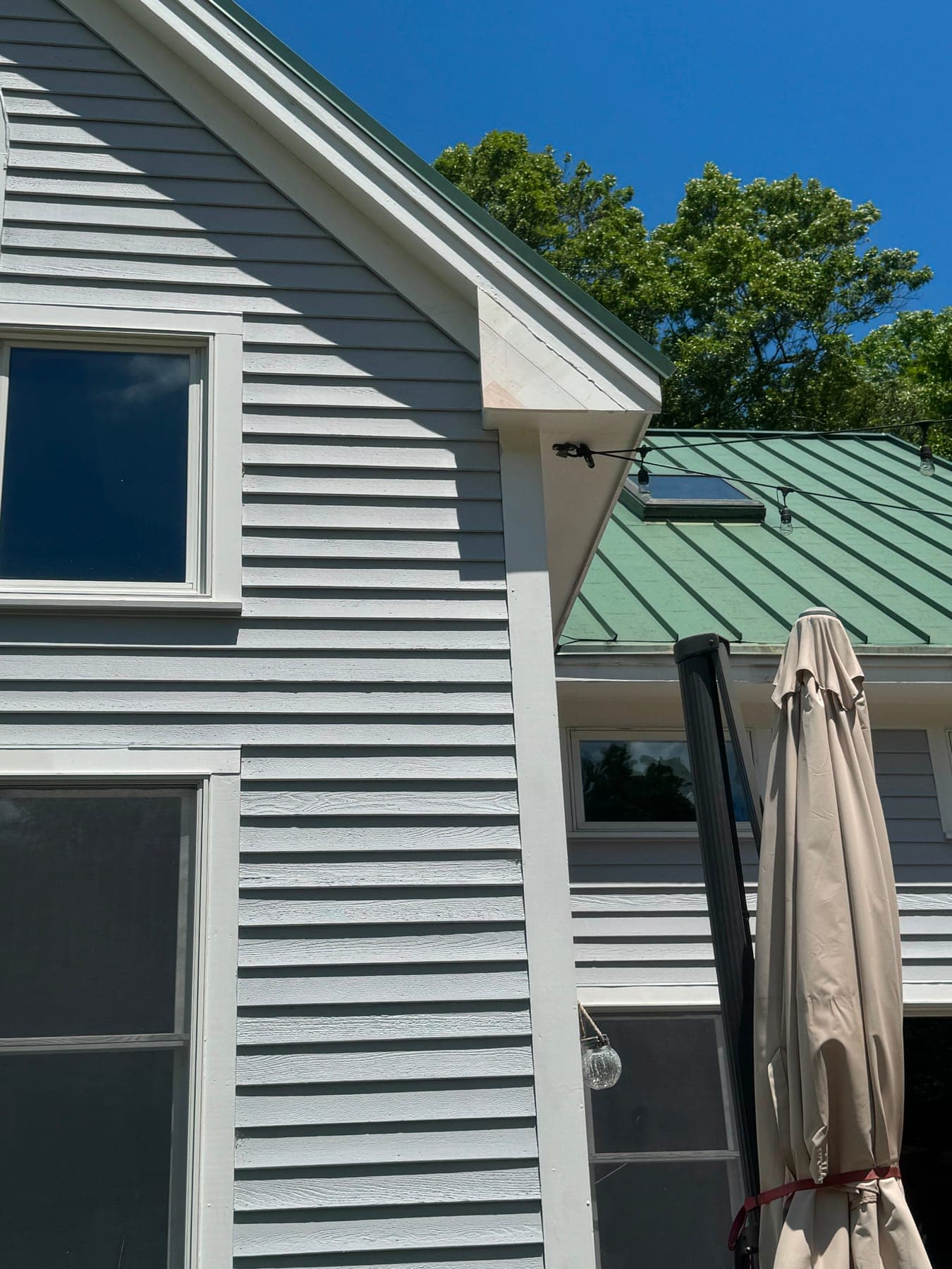 A window with new casing beside the corner of a clapboard house