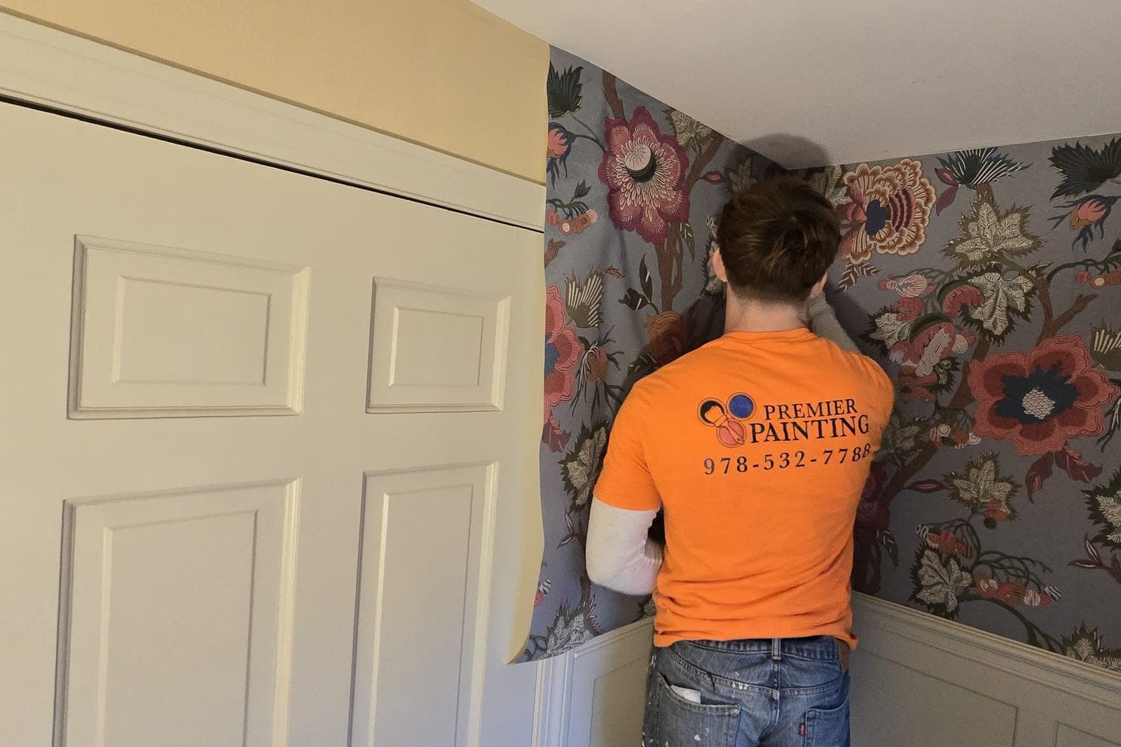 Installer in a Premier shirt fitting a grey floral paper around a door casing
