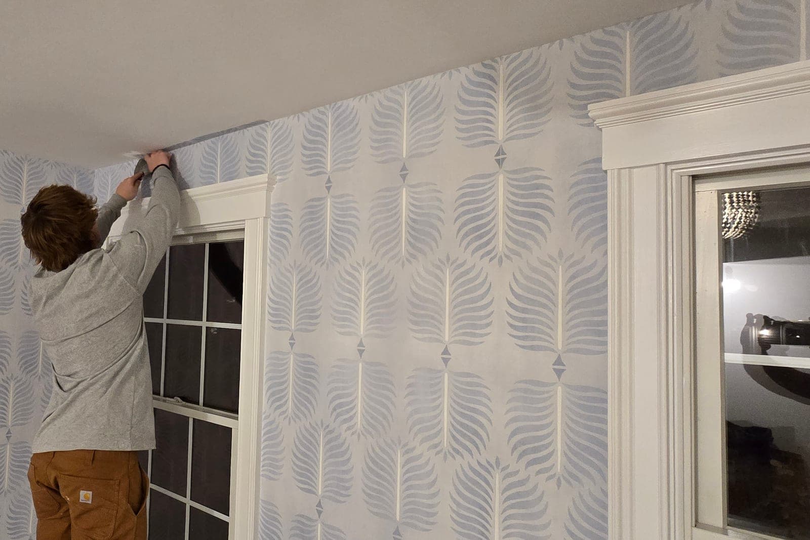 Installer smoothing a leaf-pattern paper around a window frame