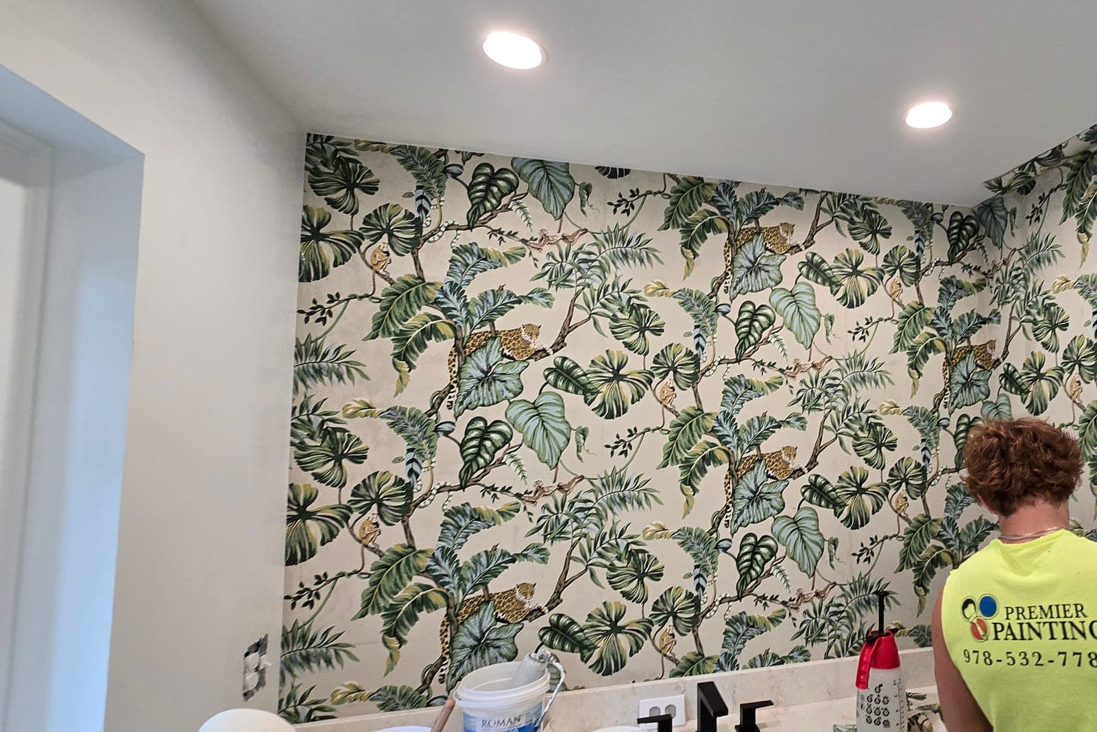 Installer in a Premier shirt hanging a tropical leaf paper