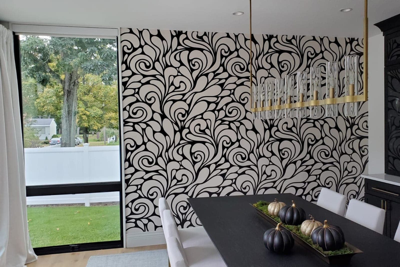 Dining room accent wall in a black-and-white scroll pattern beside a wall of windows