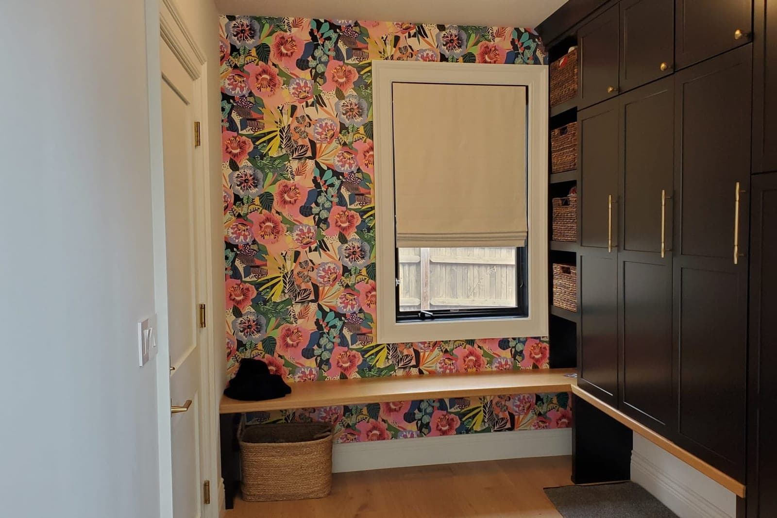 Mudroom with bright floral wallpaper, a bench seat and dark built-in cabinets